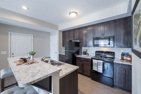 A kitchen with a marble countertop and dark wood cabinets.