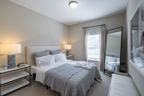 A bedroom with a large bed and a window with curtains.