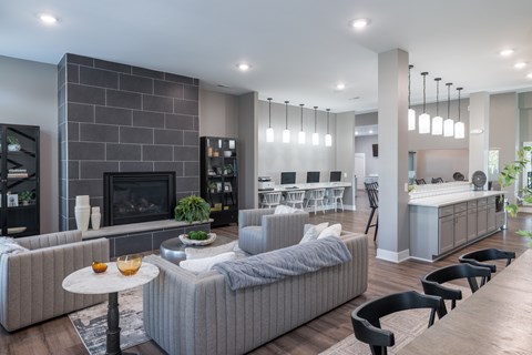 A modern living room with a grey sofa, a fireplace, and a dining area in the background.