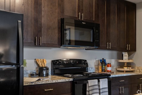 A kitchen with a black fridge, black microwave, and black stove.