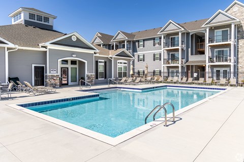 A swimming pool in front of a multi-story apartment building.