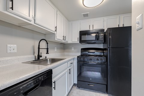 A black oven and microwave in a kitchen with white cabinets.
