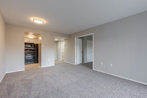 A spacious living room with a fireplace and carpeted floor.