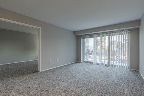 A room with a carpeted floor and a window with blinds.