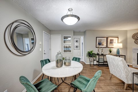 A white round table with green chairs in a room.
