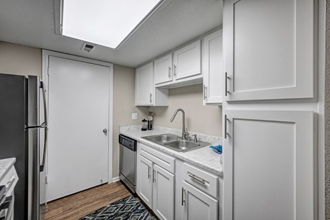 A kitchen with white cabinets and a black refrigerator.