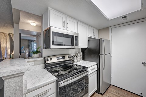 A kitchen with a stove, microwave, and refrigerator.