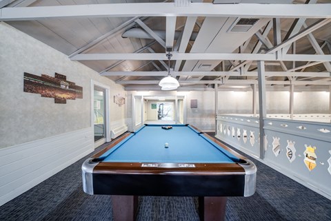A pool table in a room with a high ceiling and exposed beams.