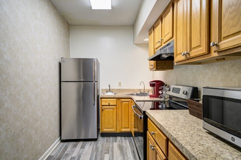 A kitchen with wooden cabinets and a stainless steel refrigerator.