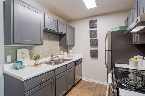 A kitchen with a stove, sink, and cabinets.