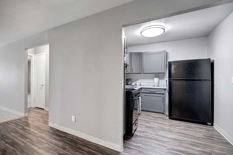 A kitchen with a black refrigerator and wooden floors.
