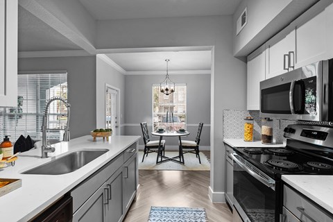 A modern kitchen with a dining table and chairs in the middle.