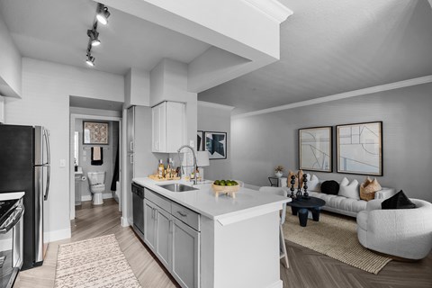 A modern kitchen with a black refrigerator and white cabinets.
