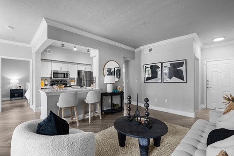 A modern living room with a kitchen in the background.