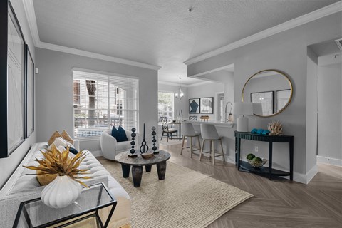 A living room with a white couch and a glass coffee table with a white pumpkin on it.