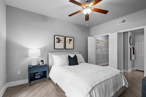 A bedroom with a white bed and a ceiling fan.