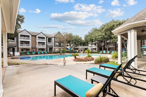 A sunny day at the poolside with lounge chairs and a swimming pool.