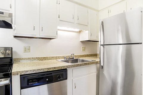 A kitchen with a stainless steel refrigerator, oven, and sink.