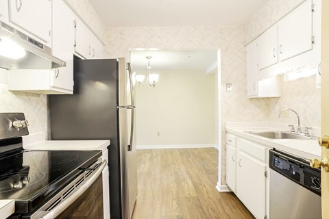 A kitchen with a black refrigerator and stove top oven.