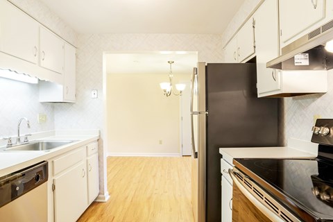 A kitchen with white cabinets and a black refrigerator.