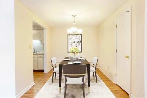 A dining room with a table set for two and a chandelier hanging from the ceiling.