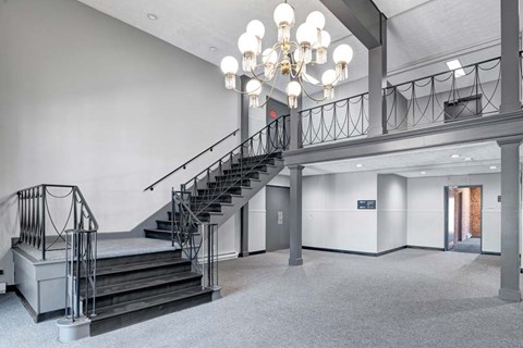 A staircase with a metal railing and a chandelier hangs from the ceiling.
