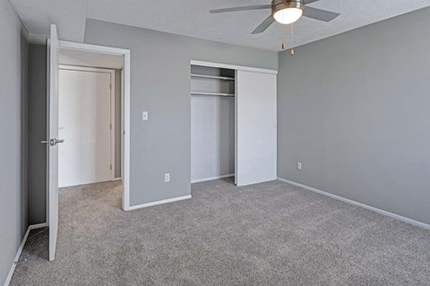 A room with a ceiling fan and two closets.
