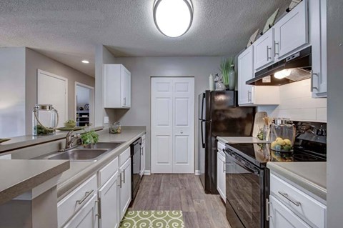 A kitchen with white cabinets and a black refrigerator.