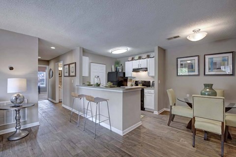 A well-lit kitchen with a bar area and a dining table with chairs.