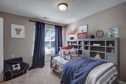 A bedroom with a bed, a bench, and a window with curtains.
