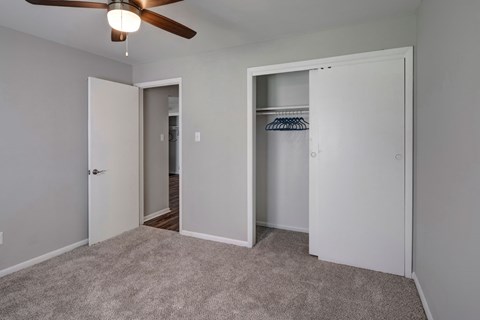 A room with a ceiling fan and two open closets.