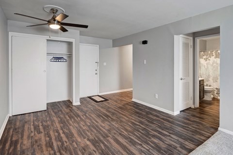 A room with a ceiling fan and wood flooring.