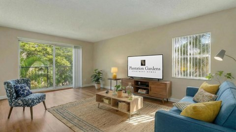 A living room with a blue couch and a television displaying the words "Plantation Gardens Community Homes".