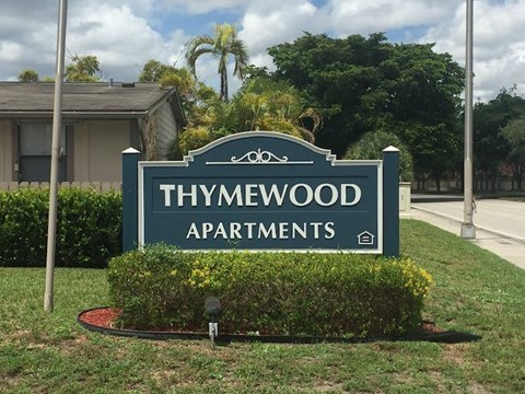 A sign for Thymewood Apartments is shown in front of a house.