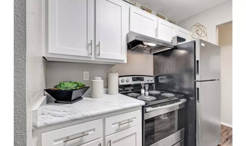A kitchen with white cabinets and a black refrigerator.