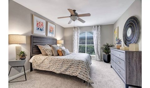 A bedroom with a bed, nightstand, and a ceiling fan.