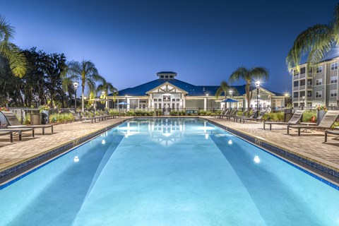 A large swimming pool in front of a building with palm trees around it.