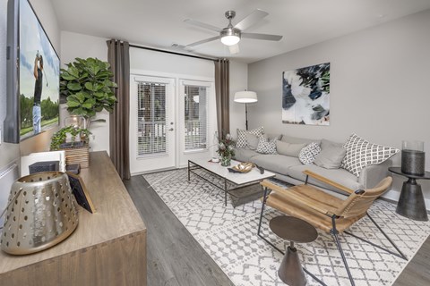 A living room with a grey couch, a wooden coffee table, and a large painting on the wall.