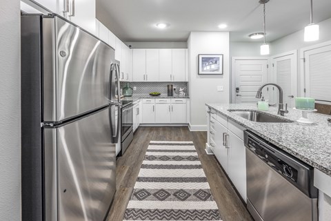 A modern kitchen with a stainless steel refrigerator and white cabinets.