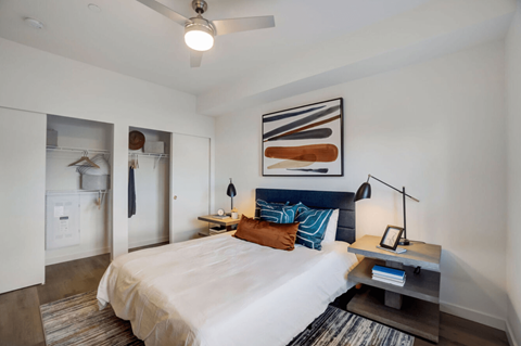 A bedroom with a bed, a nightstand, and a ceiling fan.