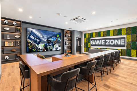 A conference room with a long table and chairs with a television screen on the wall.