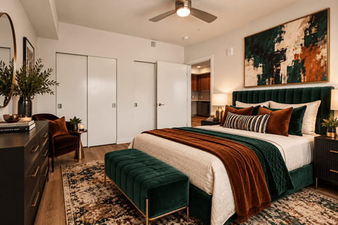 A bedroom with a large bed and a green velvet ottoman.