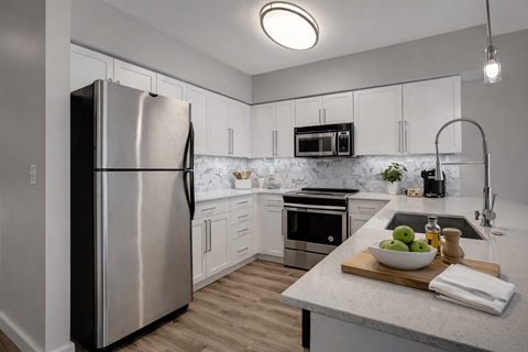 A modern kitchen with a stainless steel refrigerator and a marble countertop.
