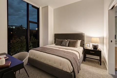 A bedroom with a large bed and a chair by the window.