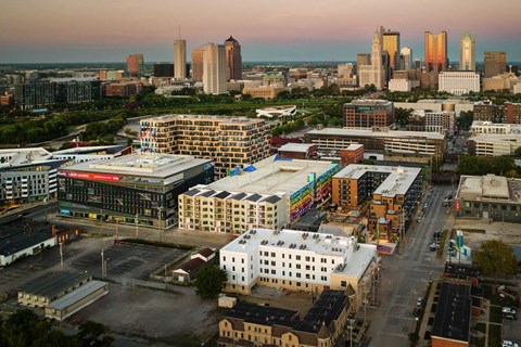 A cityscape with buildings and a parking lot in the foreground.