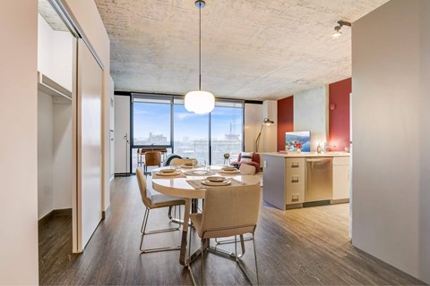 A dining room with a table set for four with a view of the city outside the window.
