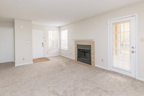 A living room with a fireplace and carpeted floor.