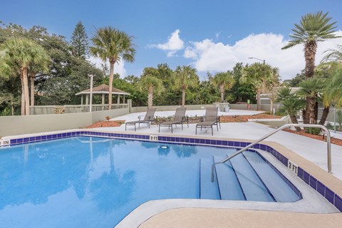 A swimming pool with a diving board and lounge chairs.