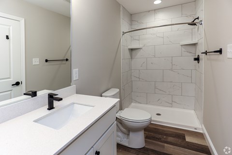 A white bathroom with a marble tile shower.