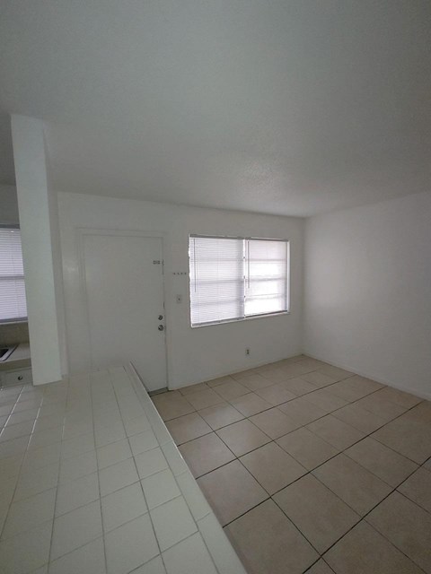 A room with a tiled floor and a window with blinds.
